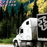 a debbie gibson truck is driving down a highway with trees in the background