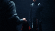 two men are standing in the dark and one of them is holding a jacket that says hugo boss