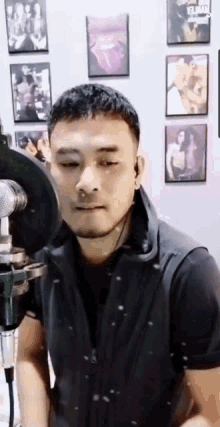 a man is singing into a microphone in a room with pictures on the wall .