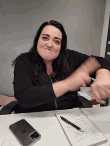a woman sitting at a desk with a pen and a notebook with a pen on it