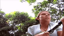 a woman is holding a sword in front of trees