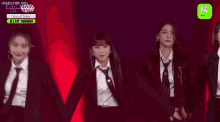 a group of girls in suits and ties are dancing on a stage .