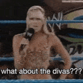 a woman in a bikini is standing in a wrestling ring holding a microphone .