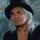 a man with long white hair is wearing a black hat
