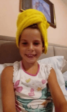 a little girl with a yellow towel wrapped around her head smiles