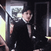a man in a tuxedo and bow tie is standing in front of stairs