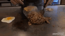 a person is cooking noodles and eggs on a griddle with the words made in animotica above them