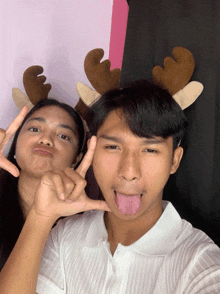 a man and a woman wearing reindeer antlers pose for a photo