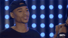 a man wearing a black hat is smiling in front of a bet star