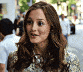 a close up of a woman wearing a necklace and a floral shirt .