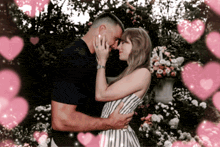 a man and a woman are hugging each other with pink hearts surrounding them