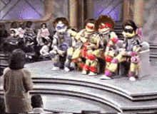 a group of teenage mutant ninja turtles are sitting on a stage in front of a crowd