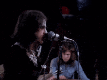 a man singing into a microphone next to a keyboard that says hohner on it