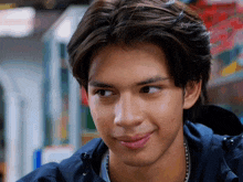 a close up of a young man 's face with a blue jacket on