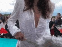 a woman in a white dress with a plunging neckline is standing on a blue carpet .