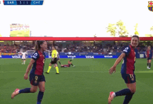 two female soccer players are celebrating a goal in front of a scoreboard that says bar 3 1 che