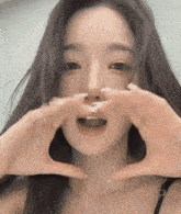 a close up of a woman making a heart with her hands .