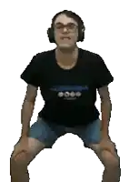 a man wearing headphones and shorts is squatting down with his legs crossed .