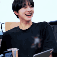 a young man wearing a black t-shirt is smiling