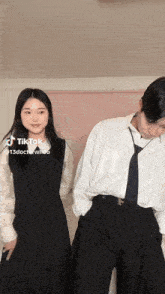 a man and a woman are standing next to each other . the woman is wearing a black dress .