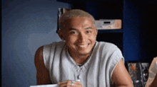 a man is smiling while sitting at a table in front of a radio .