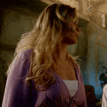 a woman in a purple top is looking down