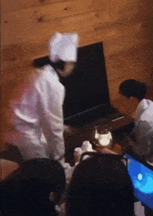 a man in a chef 's hat is standing in front of a laptop computer
