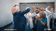 a group of doctors and nurses are standing in a hallway with nbc written on the bottom