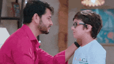 a man and a boy are looking at each other in a living room . the boy is wearing glasses .