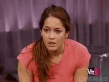 a woman in a pink shirt is making a funny face while sitting on a couch .