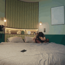 a person sitting on a bed with a cell phone on the bed