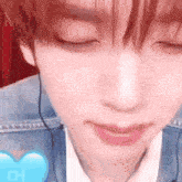 a close up of a young man 's face with his eyes closed and a heart in the background .