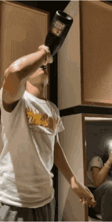 a man in a thrasher t-shirt is holding a bottle over his head