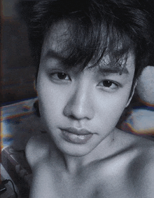 a black and white photo of a shirtless young man 's face