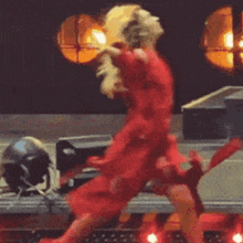 a woman in a red dress is dancing on a stage in front of a crowd .