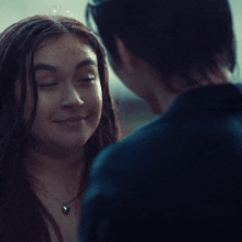 a woman wearing a heart shaped necklace looks at a man