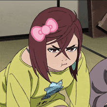 a girl wearing a yellow shirt with a fish on it has a pink bow in her hair