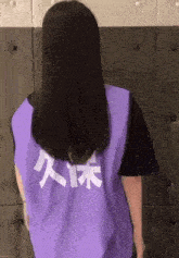 a woman wearing a purple vest with chinese writing on it
