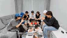 a group of young men are sitting around a table eating food and talking
