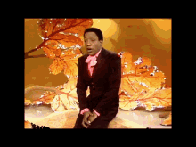 a man in a suit and bow tie is dancing on a stage with leaves in the background