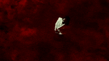 a man in a white shirt is standing in a dark room with red smoke coming out of it .