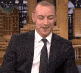 a man in a suit and tie is smiling and looking at the camera
