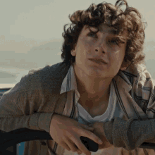 a young man with curly hair and a striped shirt