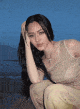 a woman with long hair is kneeling on the beach