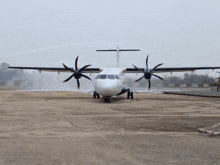 a plane is sitting on a runway with a spray of water coming out of the wing