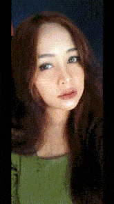 a woman with long brown hair is wearing a green sweater