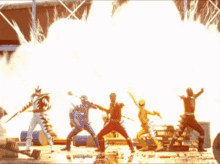 a group of power rangers are standing in front of a fire