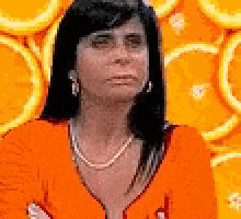 a woman wearing a pearl necklace is standing in front of orange slices ..