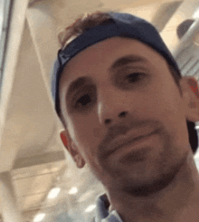 a man wearing a blue hat looks at the camera and smiles