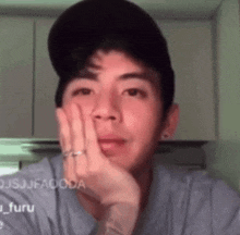 a man wearing a baseball cap and a ring on his finger is looking at the camera